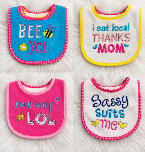 Four colorful baby bibs new with tags on a white rug