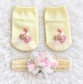 Baby girl swan socks and floral headband set on white rug