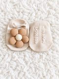Beige baby socks with fabric flower on white rug
