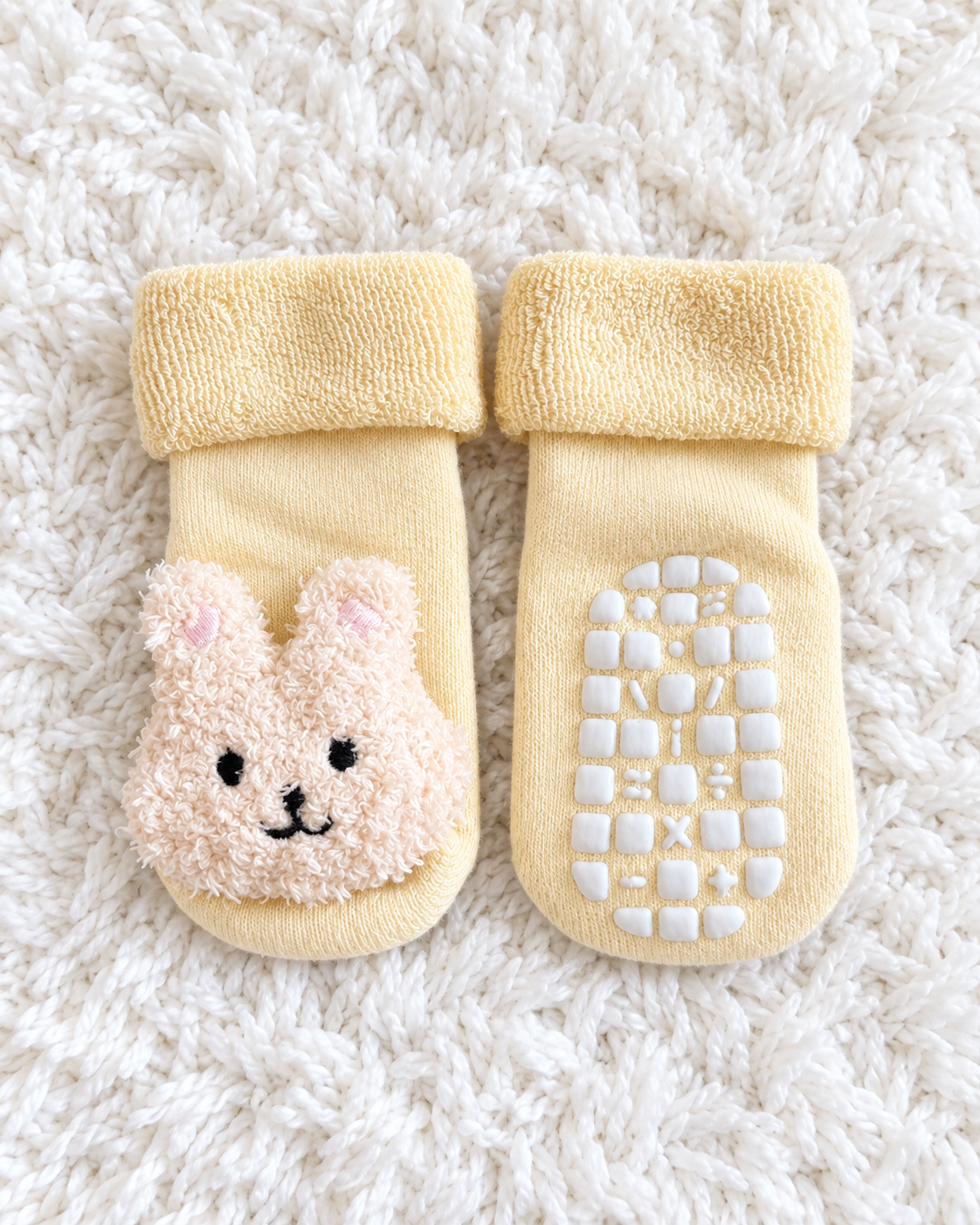 Cream bunny baby non-slip socks on white rug background