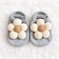 Gray baby floral sock shoes with cream flowers on white rug background