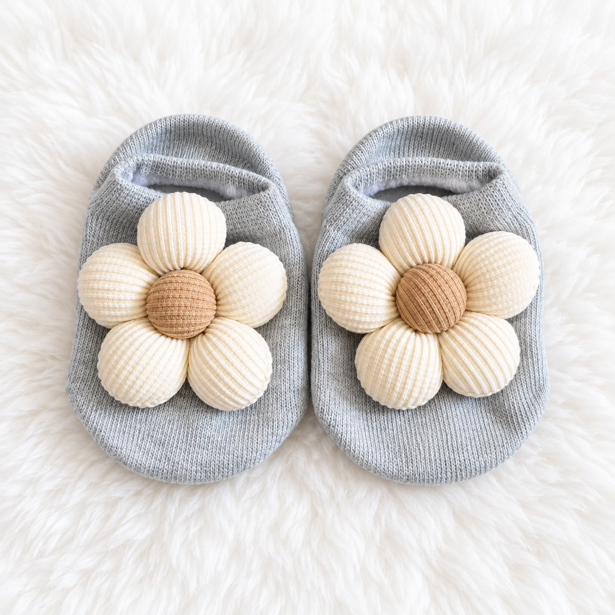 Gray baby floral sock shoes with cream flowers on white rug background