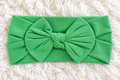 Green bow baby headband on white rug