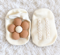 Ivory baby socks with beige flower on white rug