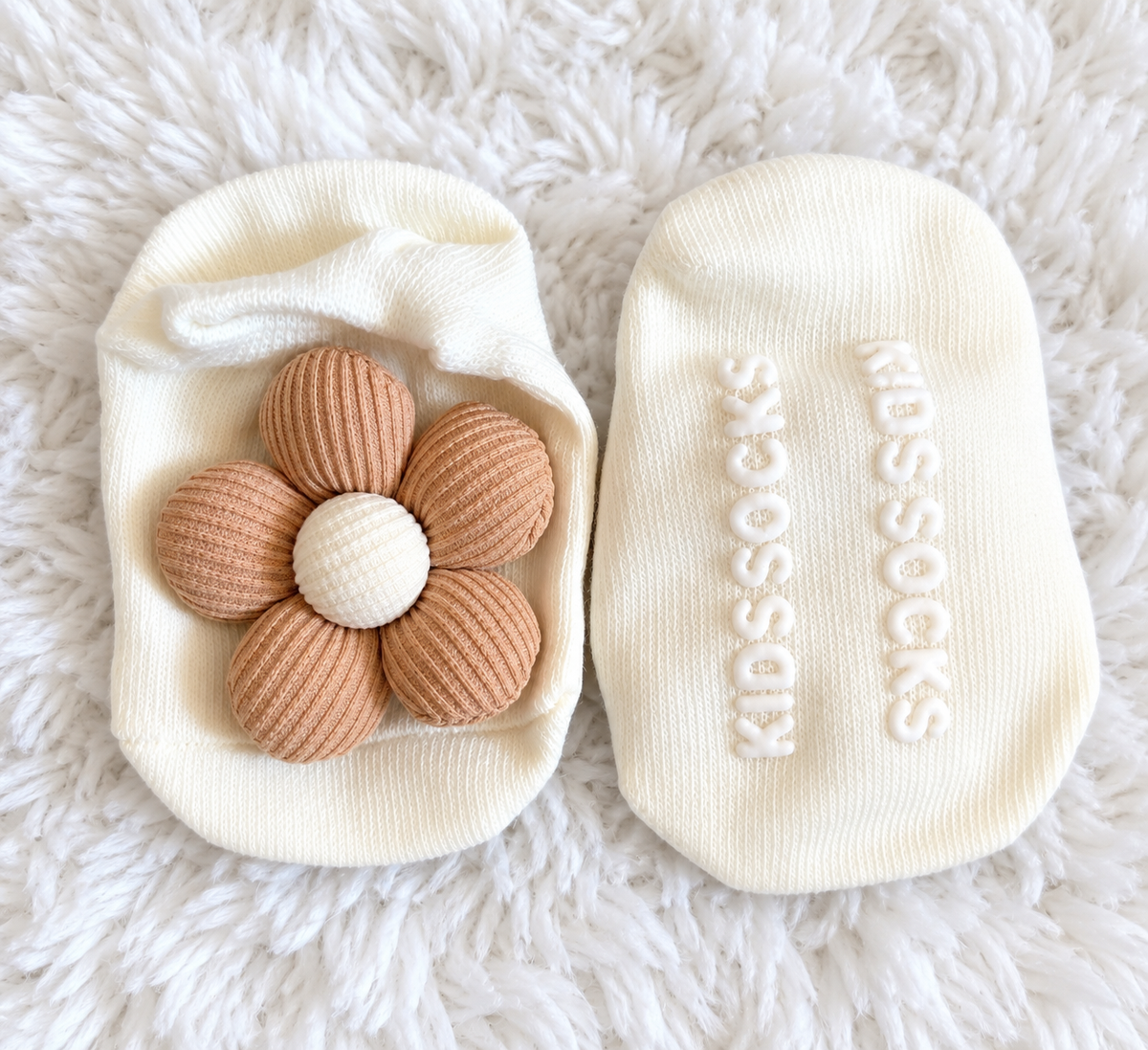 Ivory baby socks with beige flower on white rug