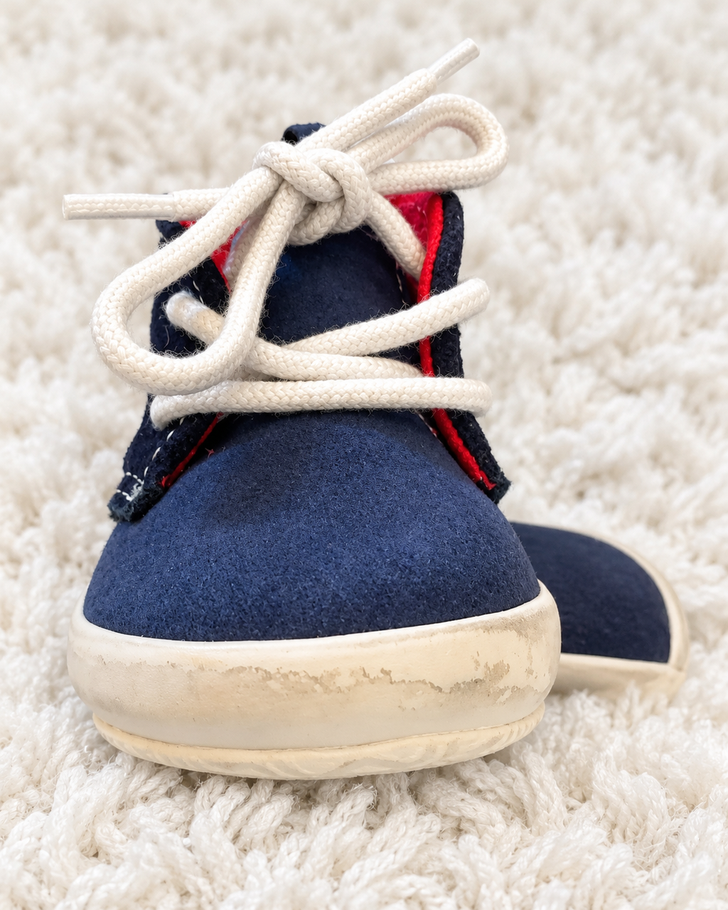 Navy baby sneaker close-up showing light wear on front sole
