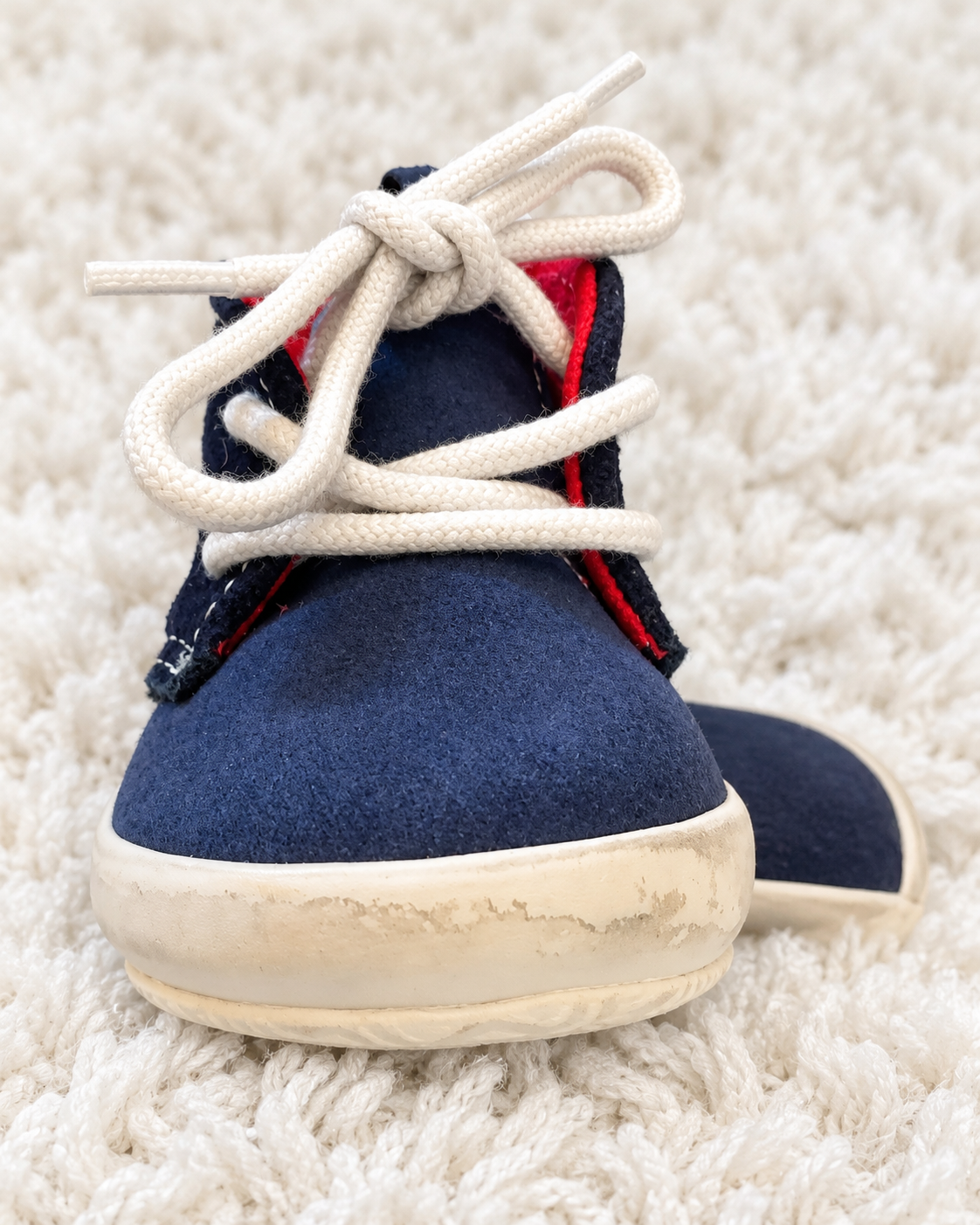 Navy baby sneaker close-up showing light wear on front sole