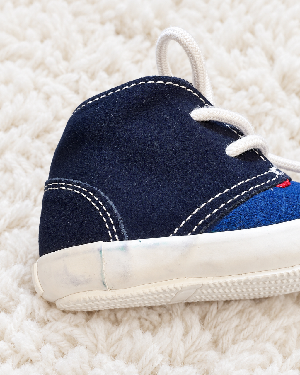 Navy baby sneaker close-up showing small marks on side sole