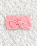 Pink baby bow headband on white rug background