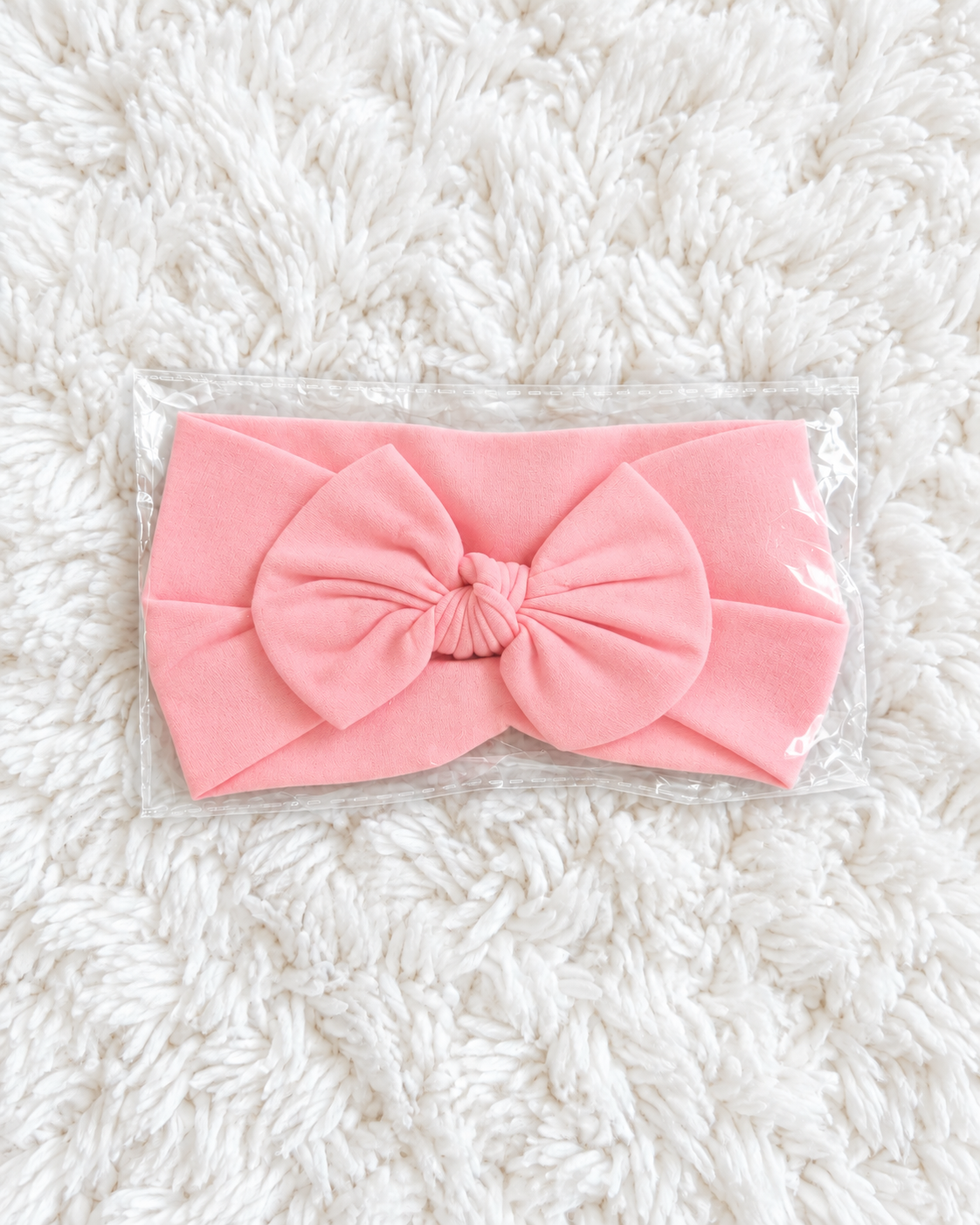 Pink baby bow headband on white rug background