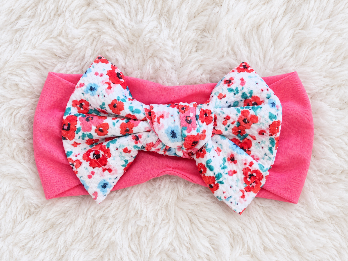 Pink floral bow baby headband on white rug
