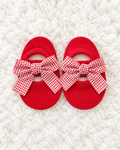 Red gingham bow baby sock shoes on white rug