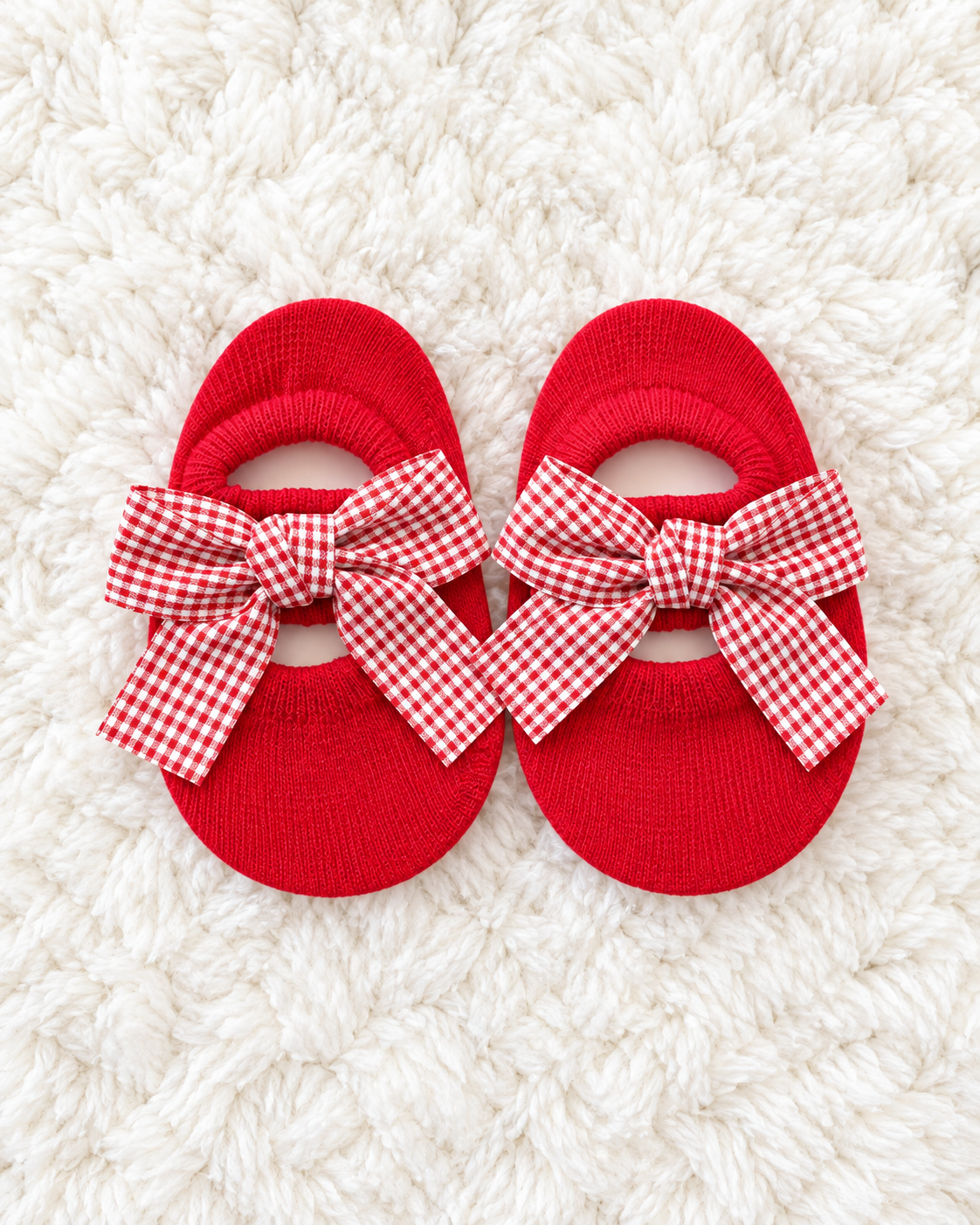 Red gingham bow baby sock shoes on white rug