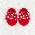 Red polka dot bow baby sock shoes on white rug