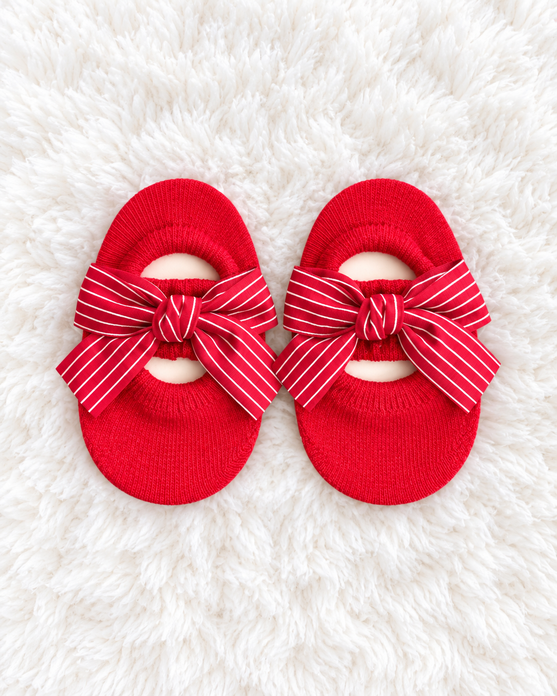 Red striped bow baby sock shoes on white rug