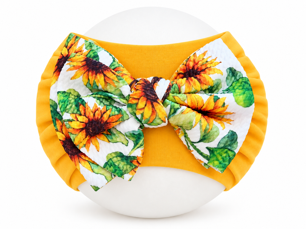Yellow sunflower bow baby headband shown expanded on round display