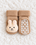 Tan bunny baby non-slip socks on white rug background
